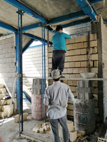 کارگران در حال دیوار چینی دیوارهای داخلی که پیش از آن اتصالات والپست تعبیه شده اند.