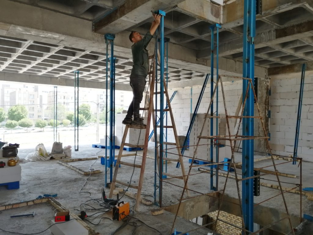 کارگران ساختمانی در حال نصب وادار و ناودانی منقطع برای اجرای دیوارهای غیرباربر.